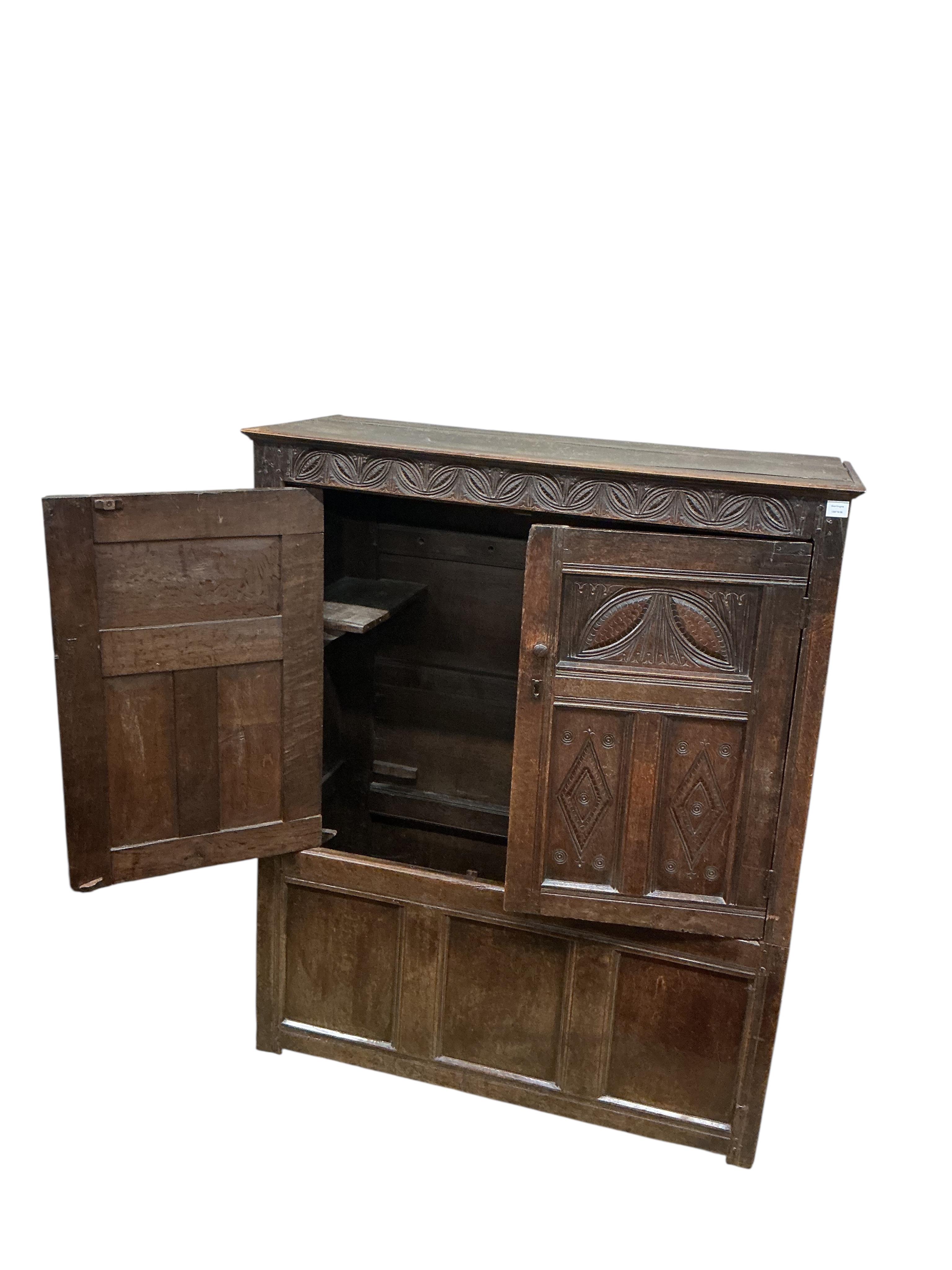 An early 18th century carved oak hanging cupboard, width 133cm, depth 56cm, height 162cm
